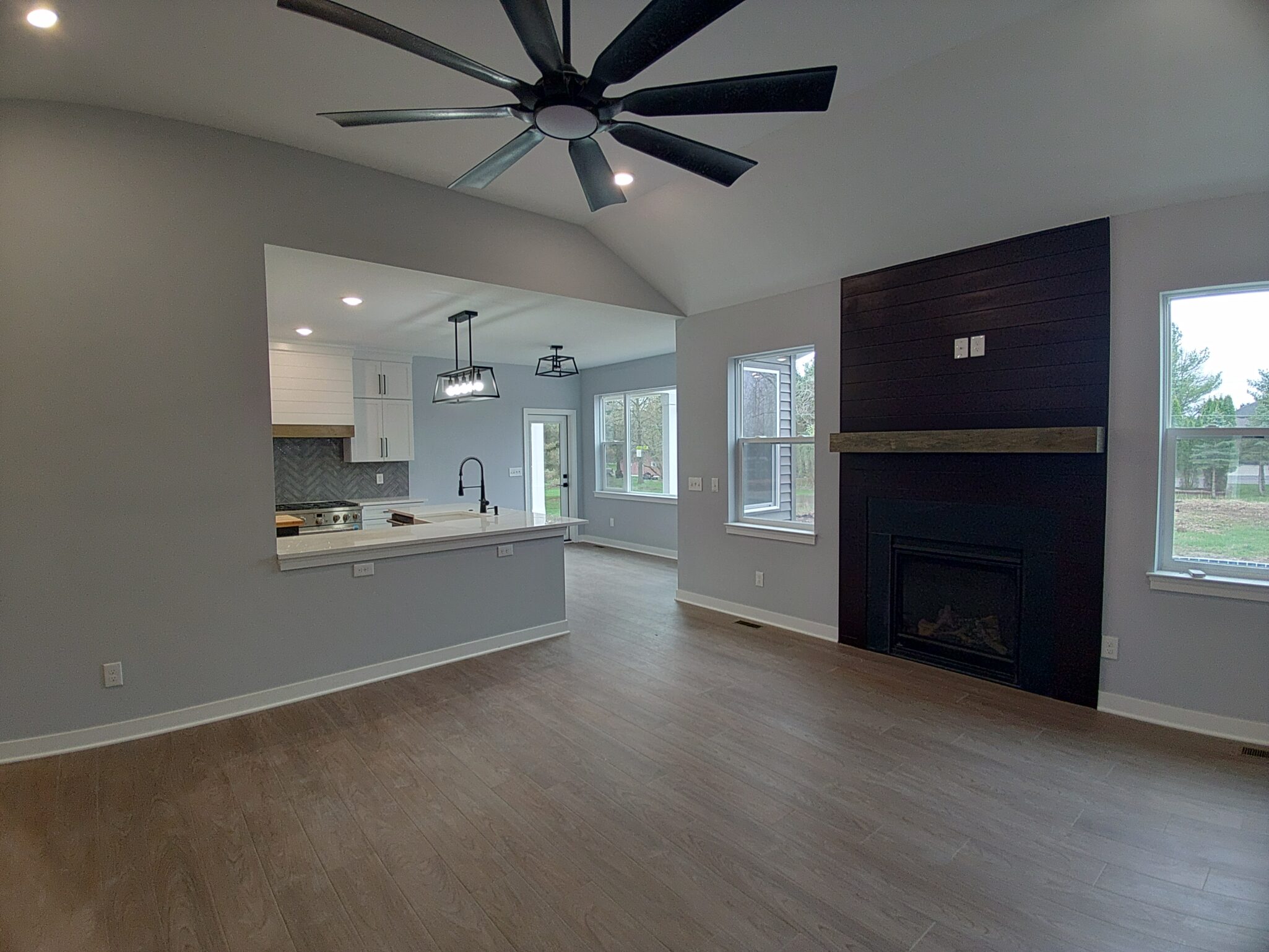 Modern living room featuring open kitchen design, large windows, and a cozy fireplace, showcasing home addition possibilities in Michigan.